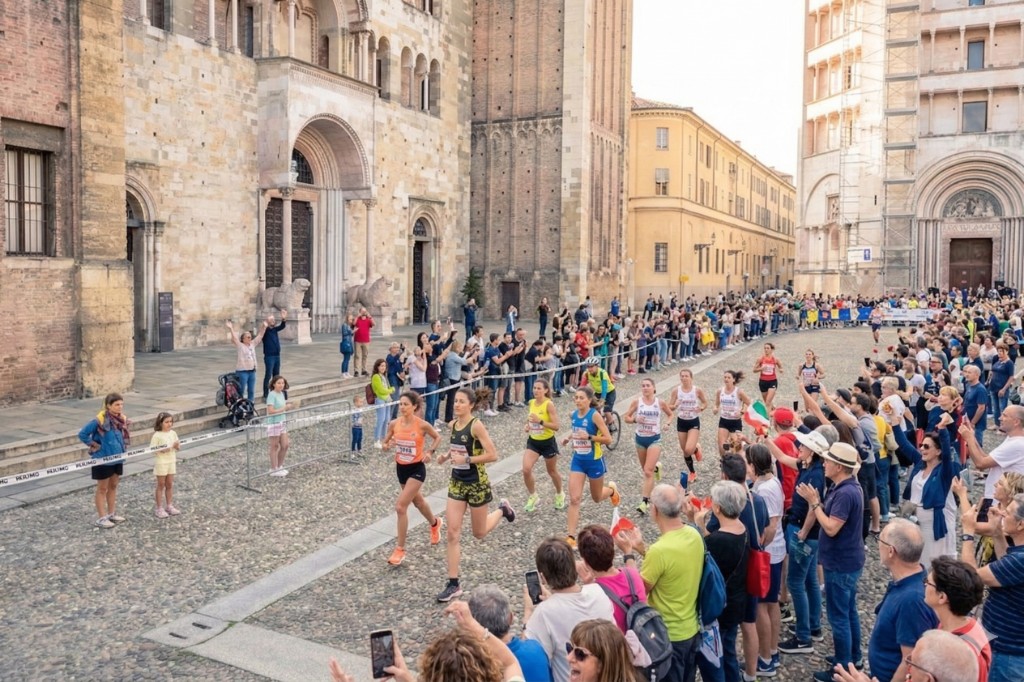 Marathon runners at Piazza Duomo in Parma — cathedral and crowds along the historic course; near Rep84 on Strada della Repubblica.